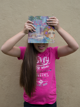 Load image into Gallery viewer, Girl holding The Elly Rose Adventures selfies from Townsville written and illustrated by Maggie O&#39;Hara pulling a funny face and having fun

